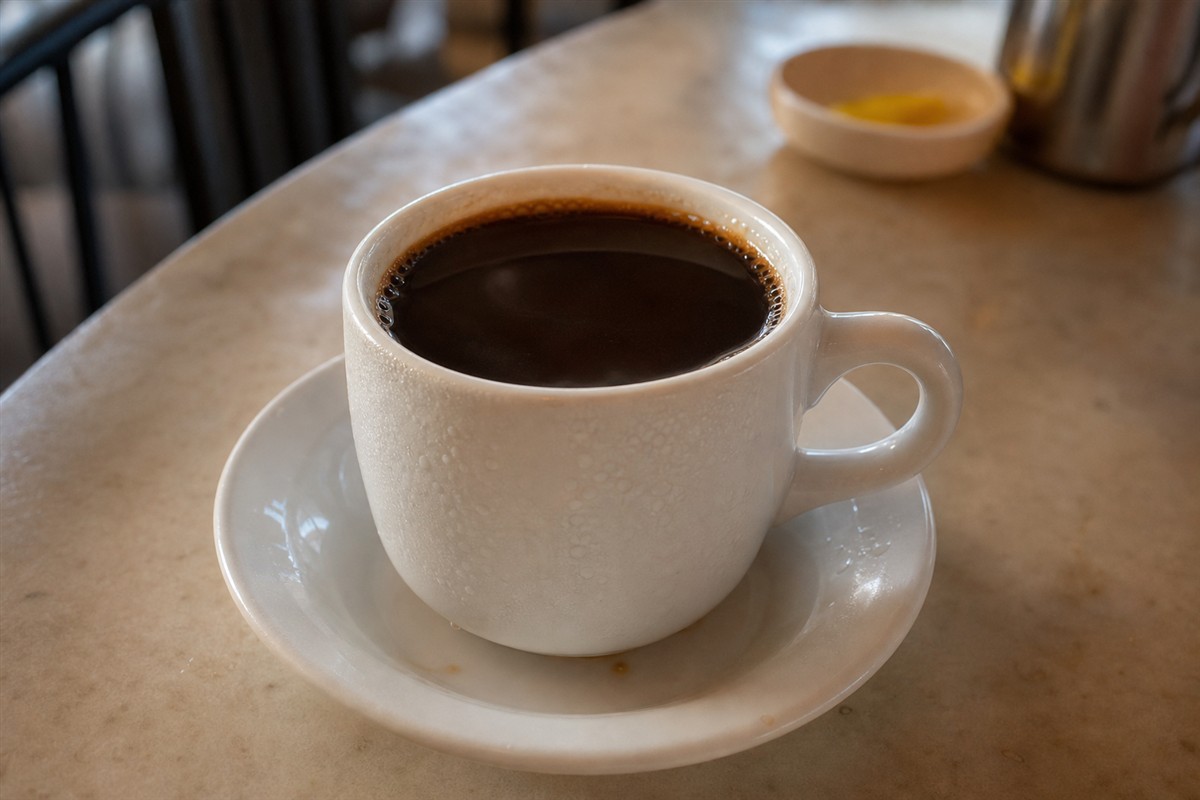 Close-up of kopi O on a saucer with condensation on the cup